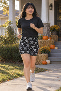 Halloween Graveyard Grey Skull & Crossbones Women's Biker Shorts worn by a model