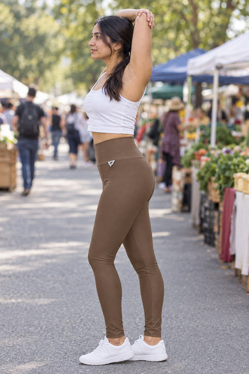 Woman wearing the Mocha Brown Essential High-Waisted Yoga Leggings with the Vantacore V emblem on the hip – side view showing the V emblem on the hip