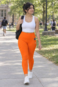 Blaze Orange Essential leggings with pockets, AI-generated fictional adult model – front three-quarter view showing the side pocket