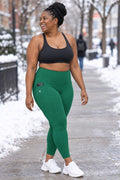 Emerald Green Essential leggings with pockets, AI-generated fictional adult model – front three-quarter view showing the side pocket
