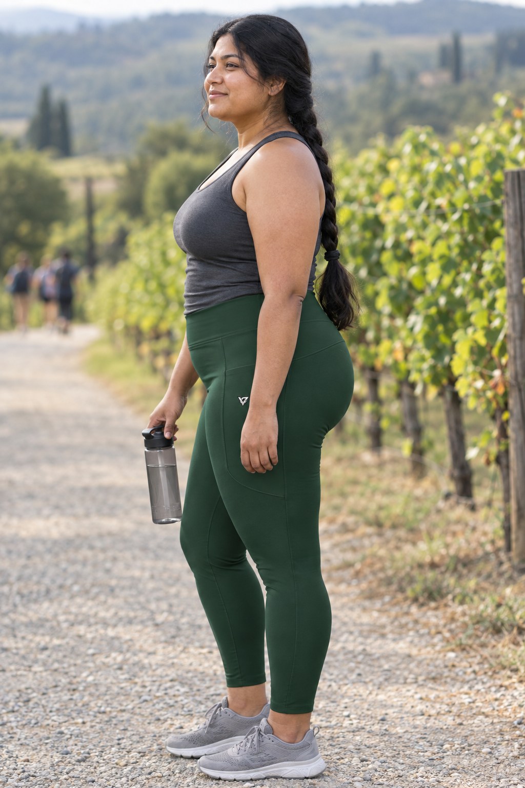 Forest Green Essential leggings with pockets, AI-generated fictional adult model – side view showing the side pocket and V emblem