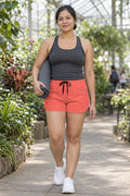 Woman wearing the Coral Essential women's athletic shorts with pockets and the Vantacore V emblem – front view