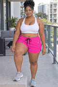 Woman wearing the Electric Pink Essential women's athletic shorts with pockets and the Vantacore V emblem – front view