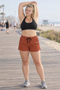 Woman wearing the Rust Essential women's athletic shorts with pockets and the Vantacore V emblem – front view