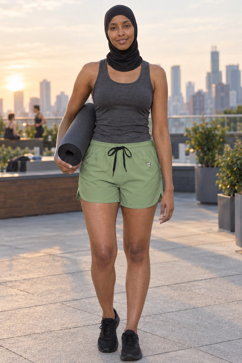 Woman wearing the Sage Green Essential women's athletic shorts with pockets and the Vantacore V emblem – front view