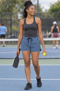 Woman wearing the Slate Blue Essential women's athletic shorts with pockets and the Vantacore V emblem – front view
