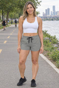 Woman wearing the Stone Grey Essential women's athletic shorts with pockets and the Vantacore V emblem – front view