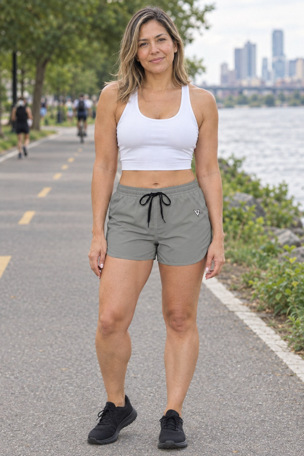 Woman wearing the Stone Grey Essential women's athletic shorts with pockets and the Vantacore V emblem – front view