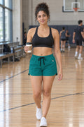 Woman wearing the Teal Essential women's athletic shorts with pockets and the Vantacore V emblem – front view