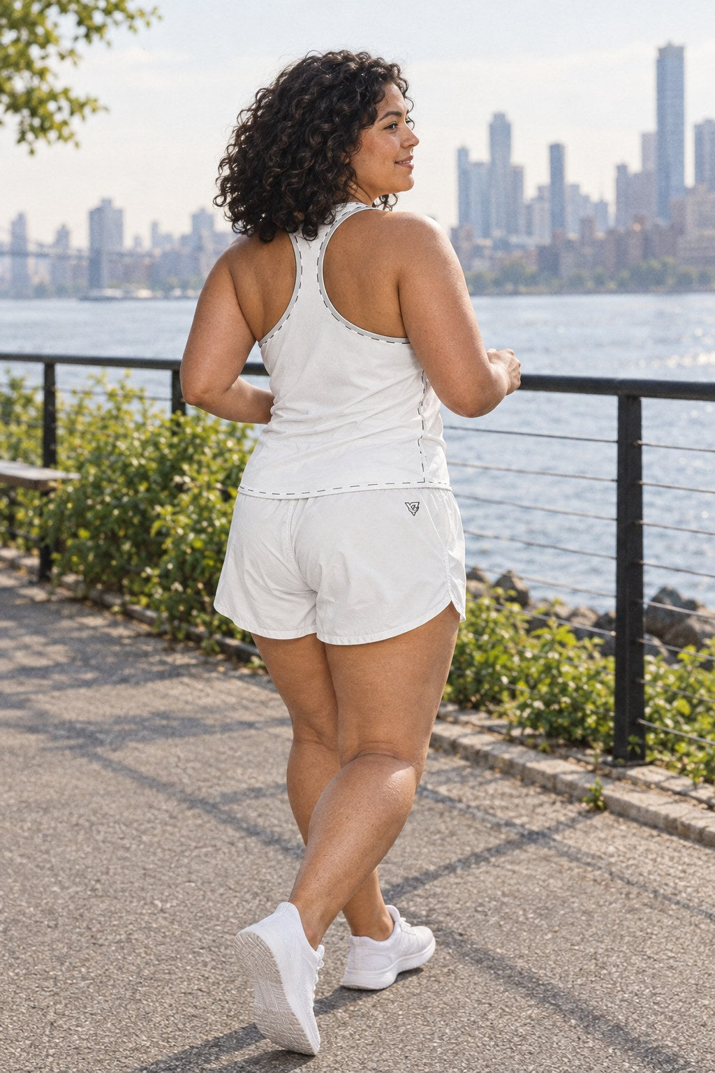Woman wearing the Arctic White Essential women's matching full-length racerback tank by Vantacore Athletics, shown with the matching pocket shorts (sold separately), side view