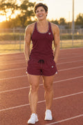 Woman wearing the Burgundy Essential women's matching full-length racerback tank by Vantacore Athletics, shown with the matching pocket shorts (sold separately)