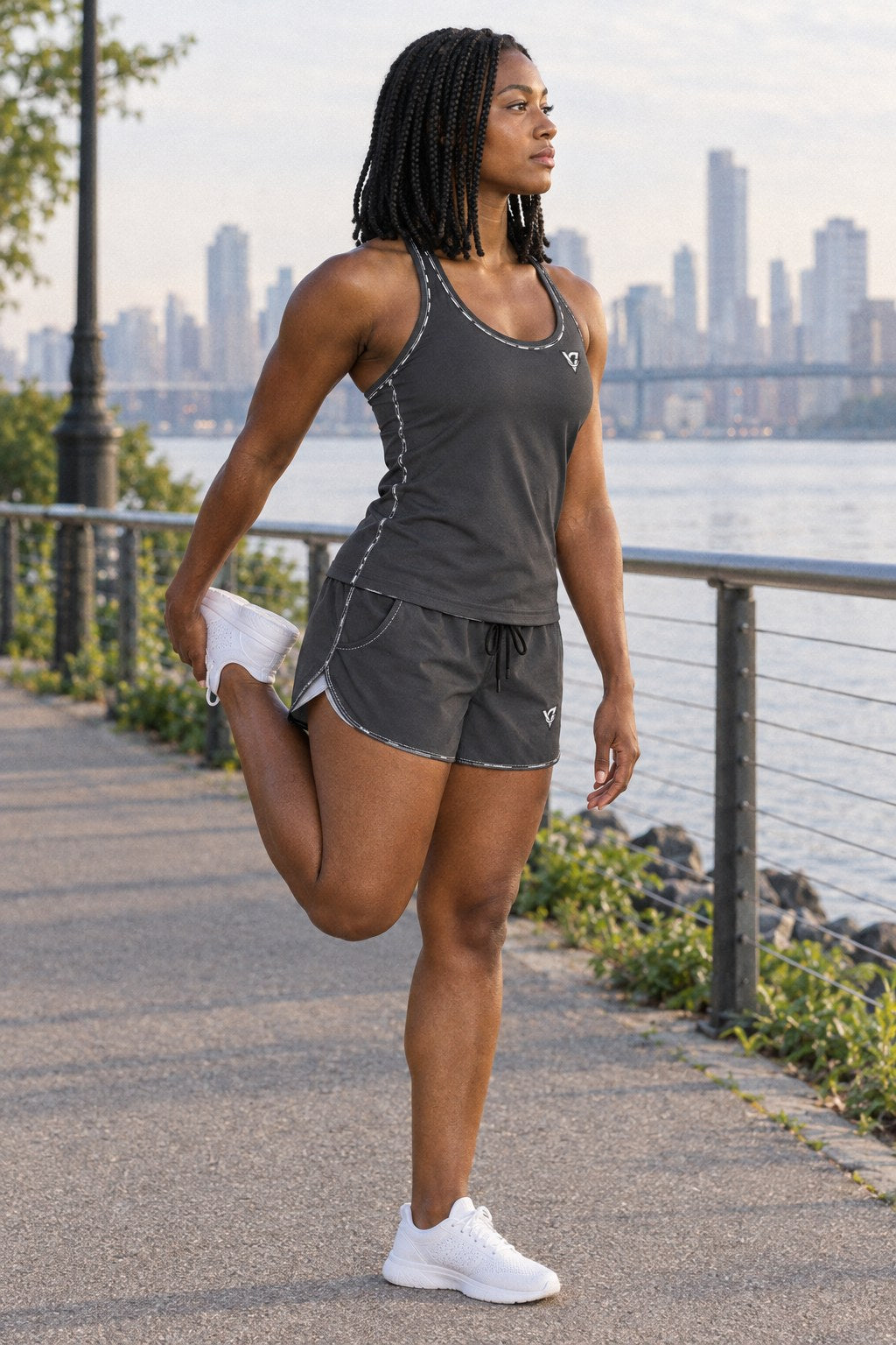 Woman wearing the Charcoal Grey Essential women's matching full-length racerback tank by Vantacore Athletics, shown with the matching pocket shorts (sold separately), side view