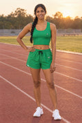 Woman wearing the Emerald Green Essential women's matching crop tank by Vantacore Athletics, shown with the matching pocket shorts (sold separately)