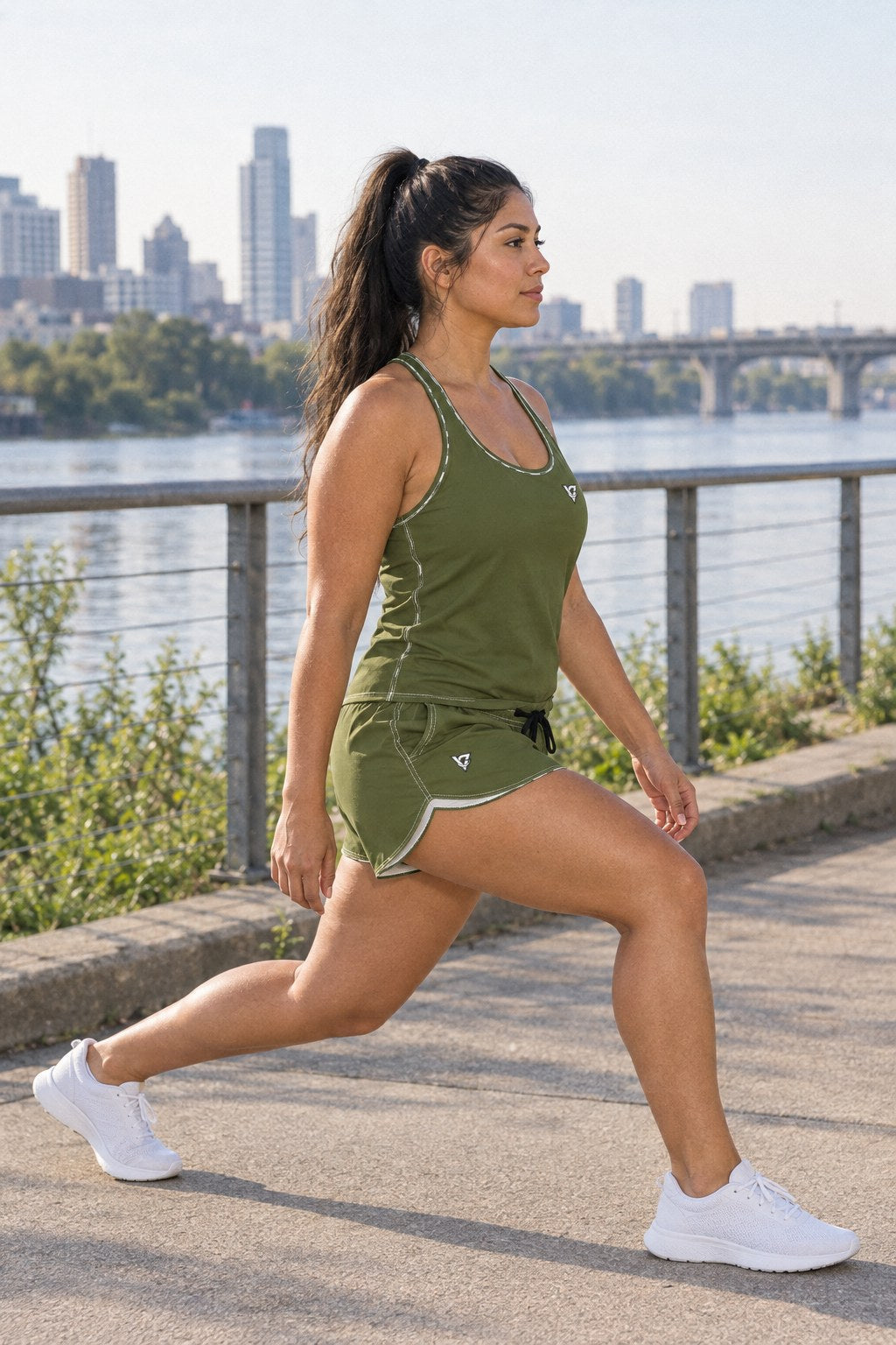 Woman wearing the Olive Green Essential women's matching full-length racerback tank by Vantacore Athletics, shown with the matching pocket shorts (sold separately), side view
