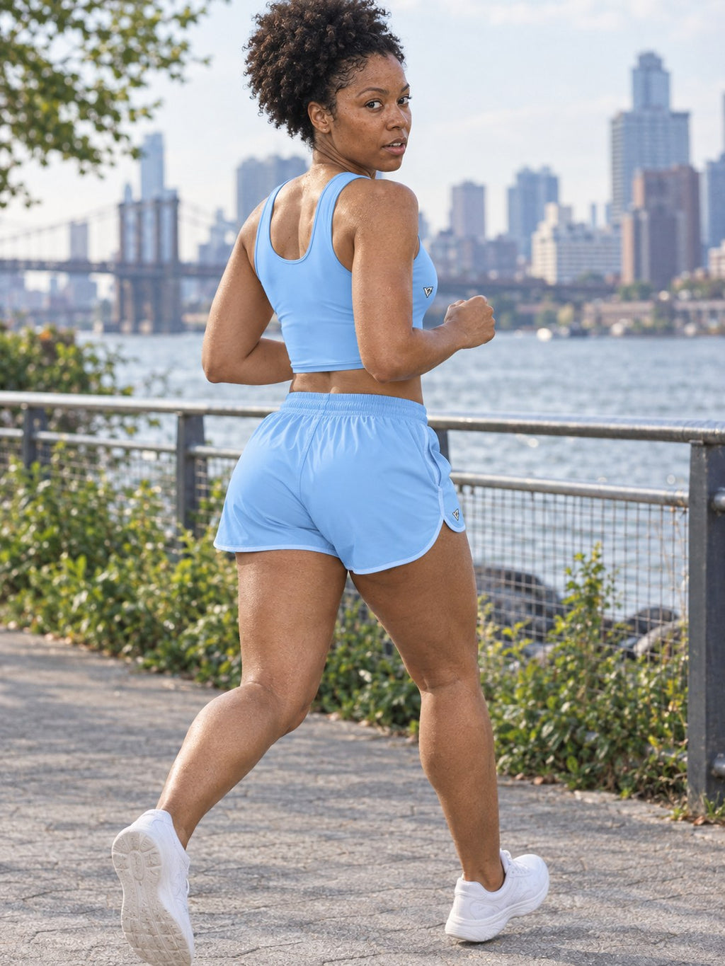 Woman wearing the Sky Blue women's matching crop tank by Vantacore Athletics, shown with the matching pocket shorts (sold separately), side view
