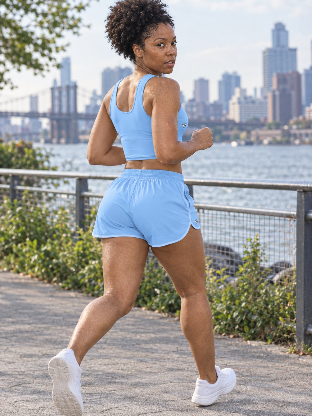 Woman wearing the Sky Blue women's matching crop tank by Vantacore Athletics, shown with the matching pocket shorts (sold separately), side view