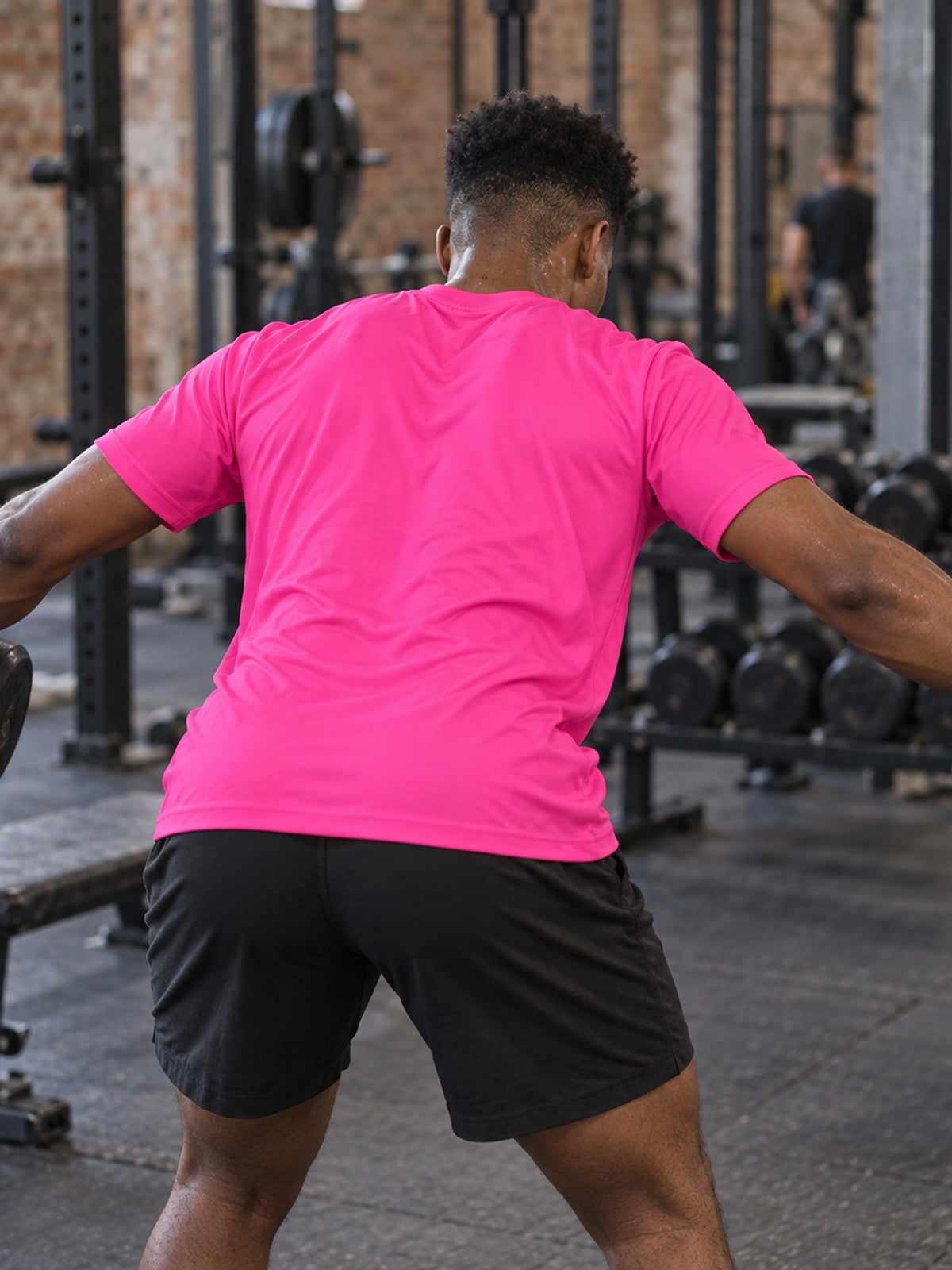 Man training in the Electric Pink Essential men's sports jersey with the Vantacore V emblem on the left chest – back view