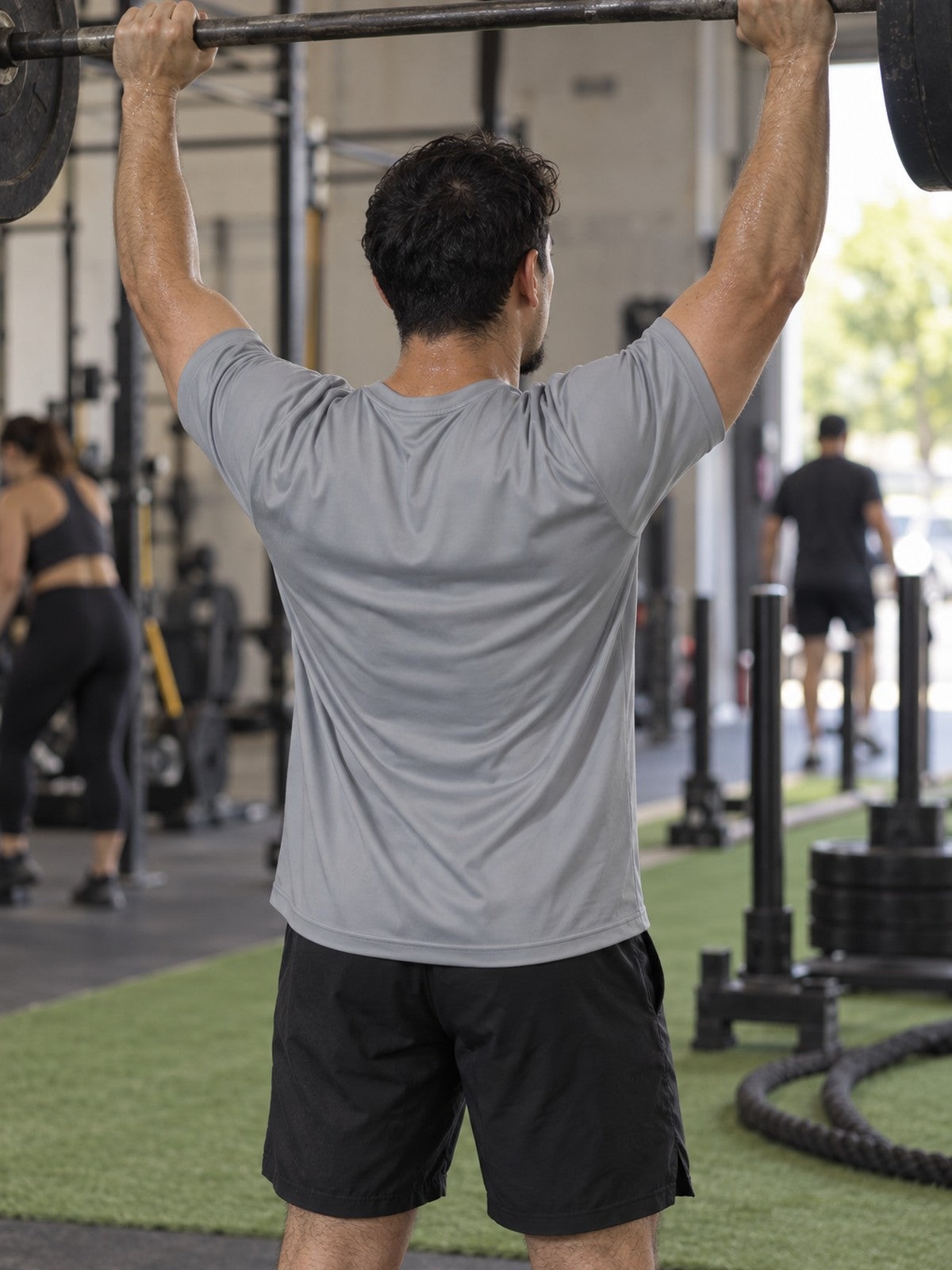 Man training in the Stone Grey Essential men's sports jersey with the Vantacore V emblem on the left chest – back view