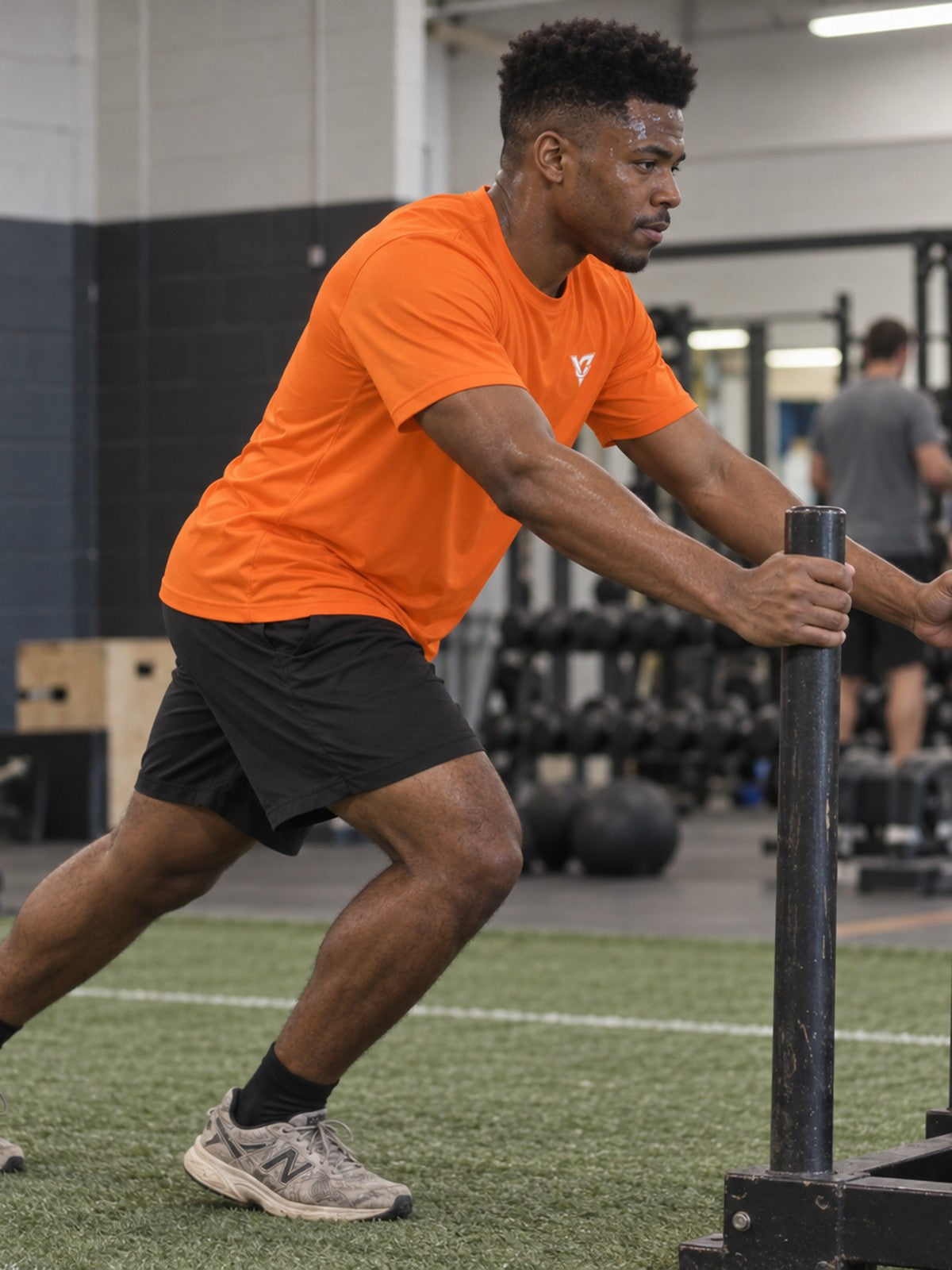 Man training in the Blaze Orange Essential men's sports jersey with the Vantacore V emblem on the left chest – side view
