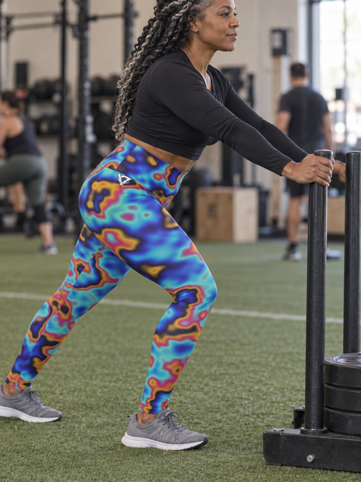 Woman wearing the Oil Slick high-waisted yoga leggings with the Vantacore V emblem on the hip – side view