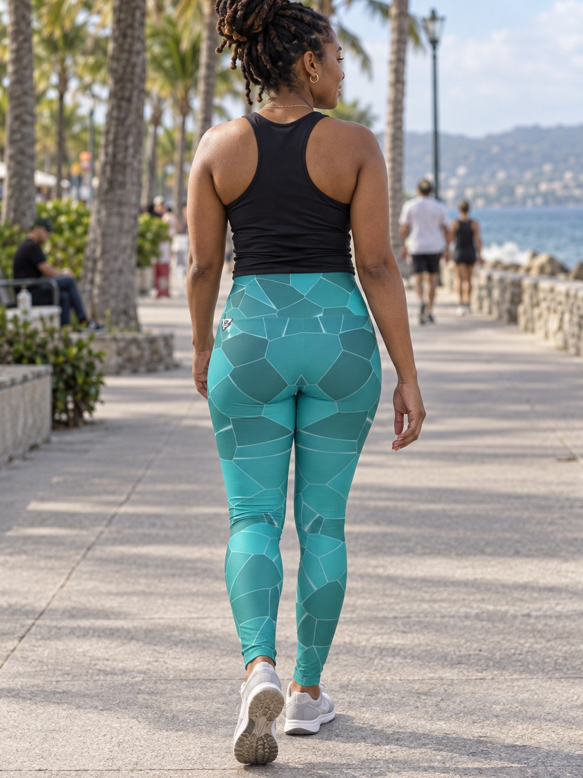Woman wearing the Turquoise Shatter high-waisted yoga leggings with the Vantacore V emblem on the hip – back view