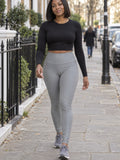 Woman wearing the Stone Grey Essential High-Waisted Yoga Leggings with the Vantacore V emblem on the hip – front view