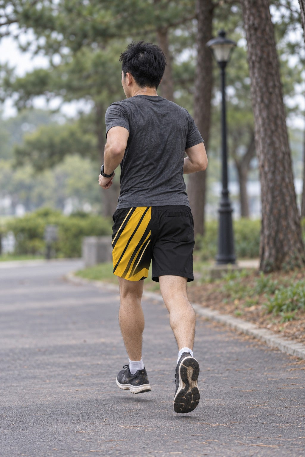 Runner wearing Men's Black & Gold Running Jogger Shorts with Pockets — Athletic Performance AOP — rear view