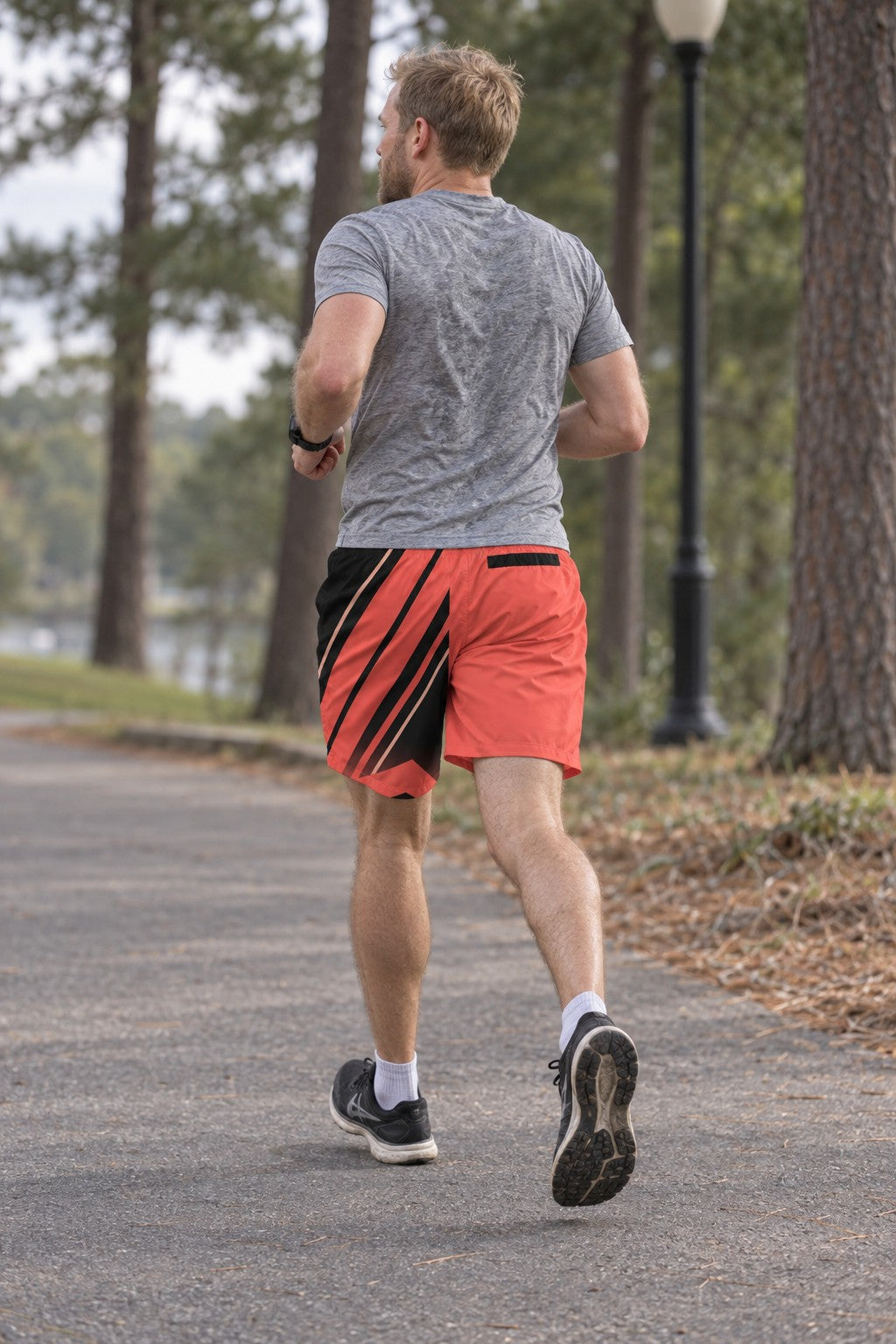 Runner wearing Men's Sunset Coral & Black Running Jogger Shorts with Pockets — Athletic Performance AOP — rear view