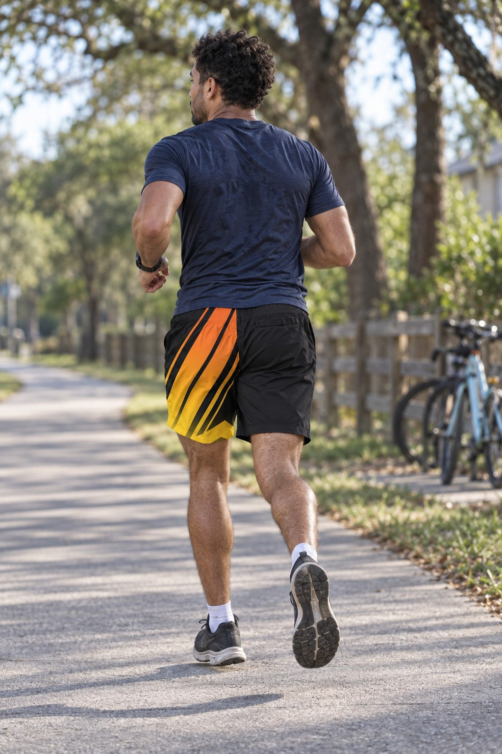 Runner wearing Men's Black Flame Orange & Yellow Running Jogger Shorts with Pockets — Athletic Performance AOP — rear view