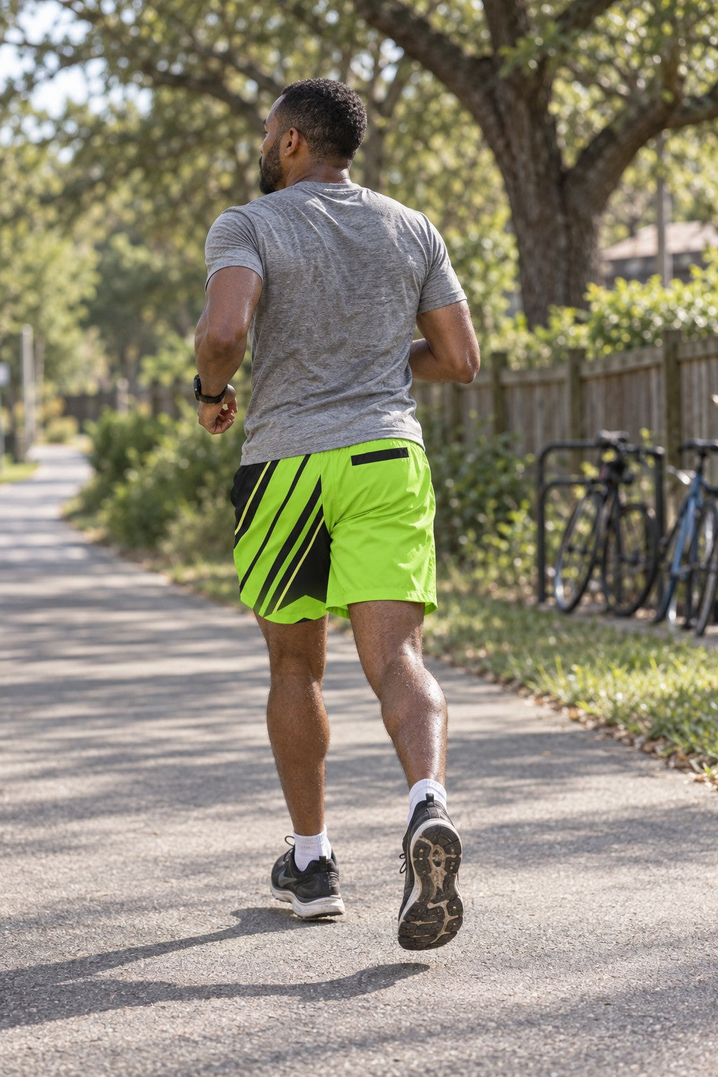 Runner wearing Men's Volt Green & Black Running Jogger Shorts with Pockets — Athletic Performance AOP — rear view
